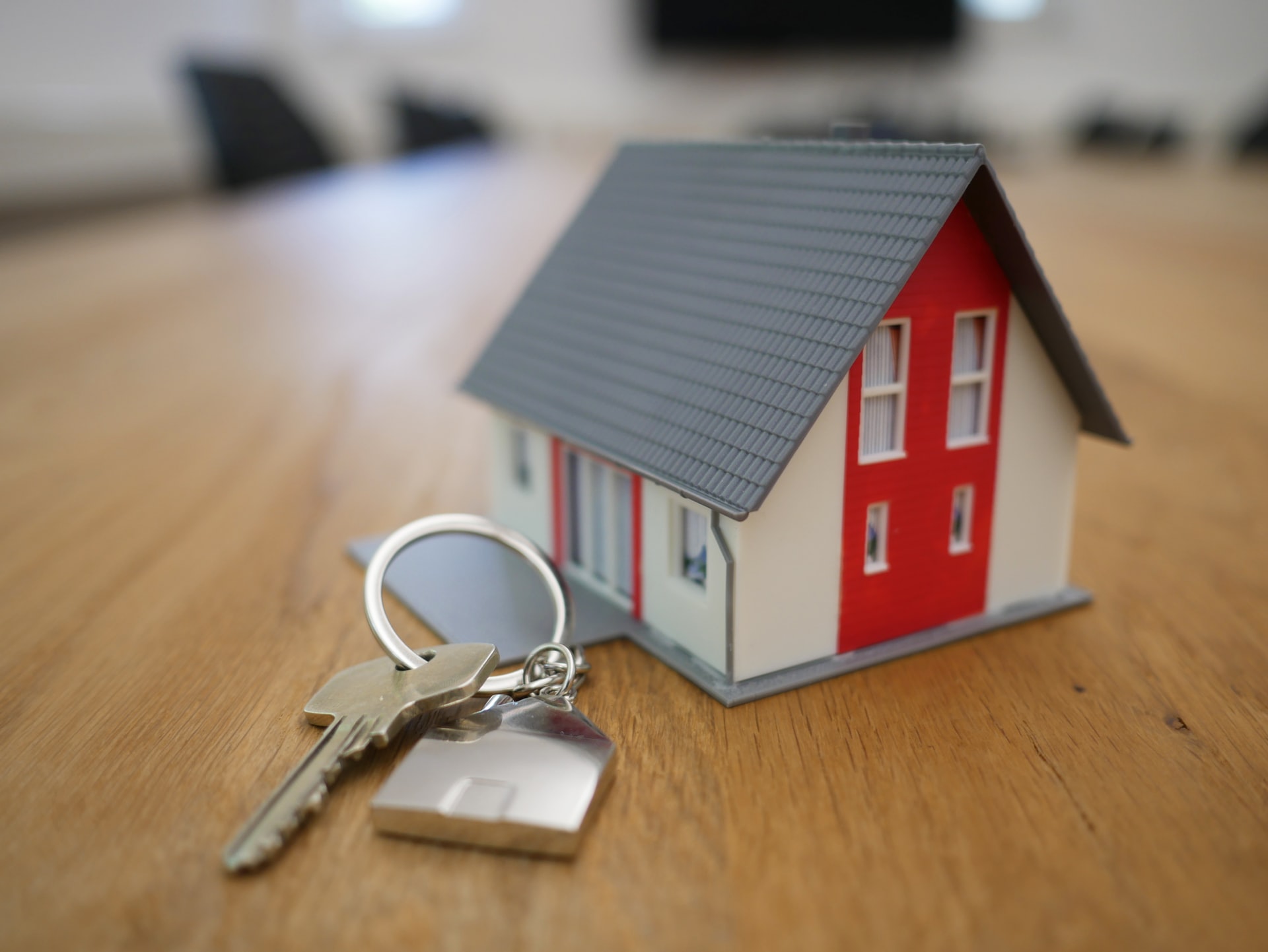 Silver Key and Keychain Next to a Small House