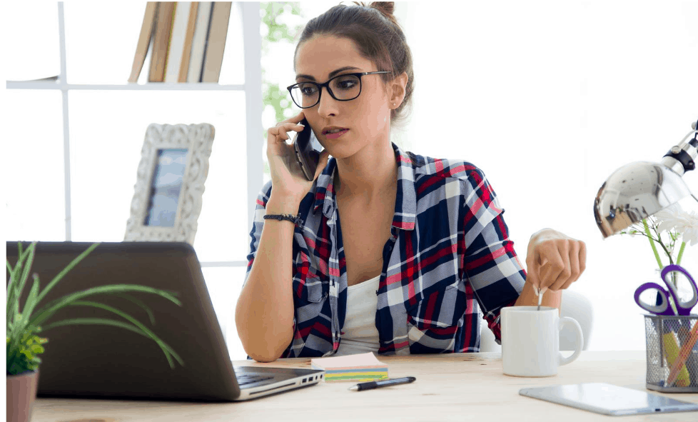 Woman talking in telephone in front of computer in an office